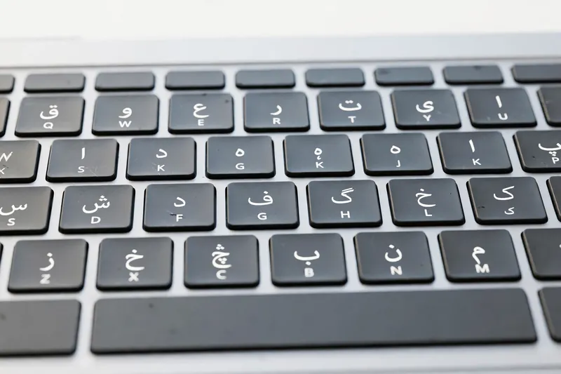 Close-up of Mac laptop keyboard with Urdu script characters on keys