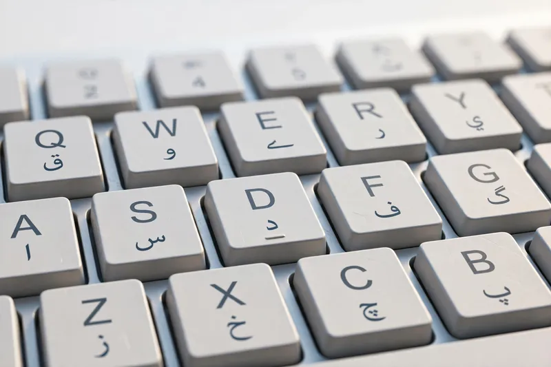 Close-up of keyboard keys with Latin letters and matching Urdu phonetic characters